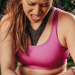 Vrouw in sportkleding houdt tijdens het sporten buiten haar pijnlijke knie vast