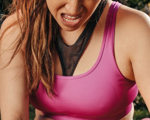 Vrouw in sportkleding houdt tijdens het sporten buiten haar pijnlijke knie vast