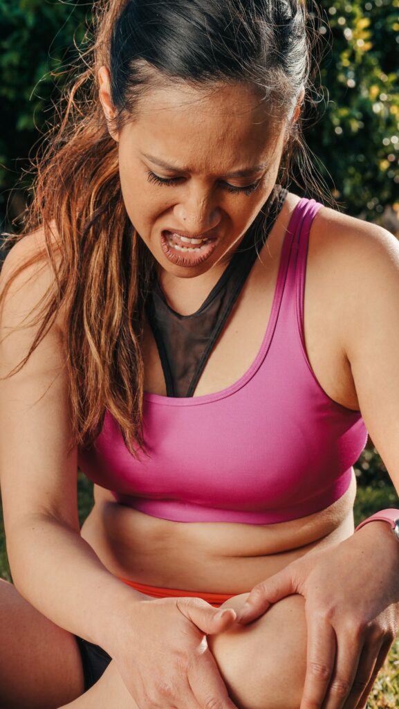 Vrouw in sportkleding houdt tijdens het sporten buiten haar pijnlijke knie vast
