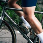 Close-up van de benen van een fietser die buiten op een racefiets aan het trappen is