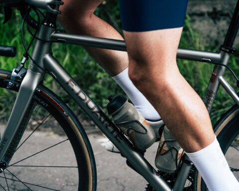 Close-up van de benen van een fietser die buiten op een racefiets aan het trappen is